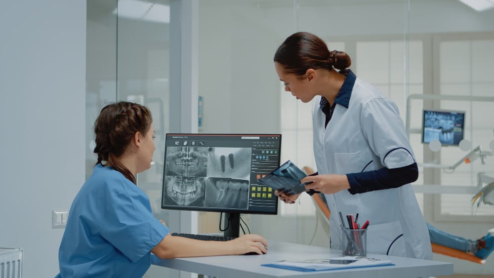 Dental professionals reviewing digital dental scans on a computer monitor