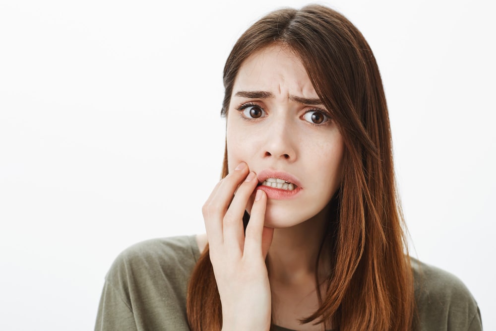 Woman touching her cheek while experiencing dental pain