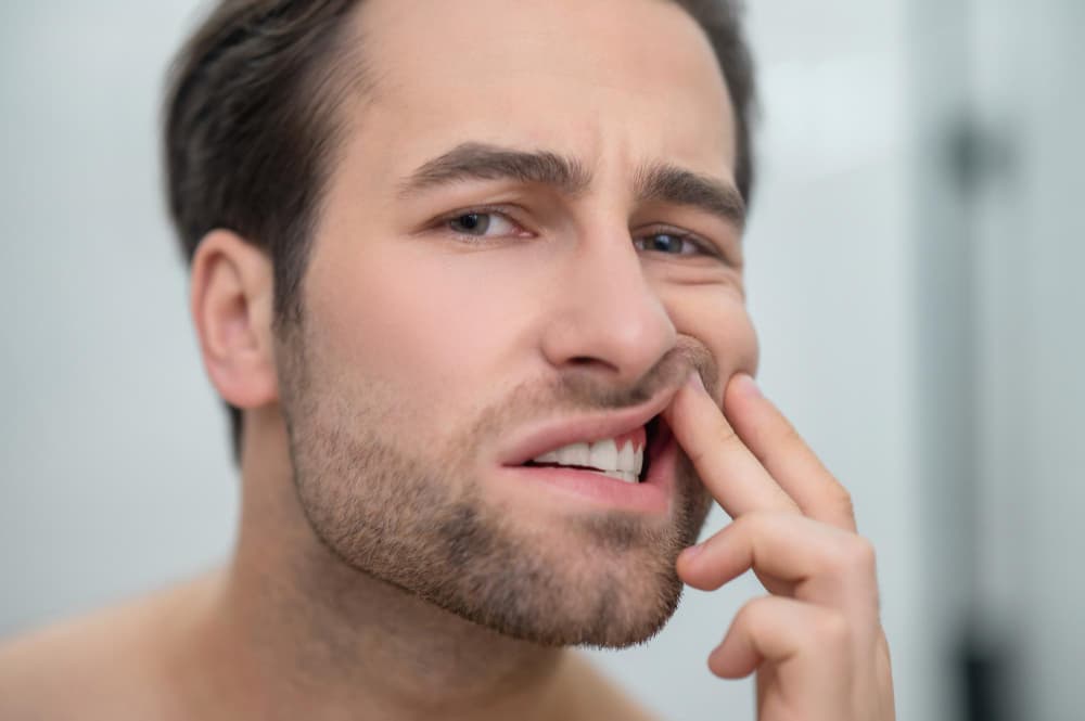 Man touching irritated gums near a painful tooth