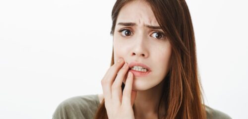 Woman touching her cheek while experiencing dental pain