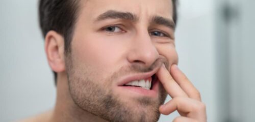 Man touching irritated gums near a painful tooth